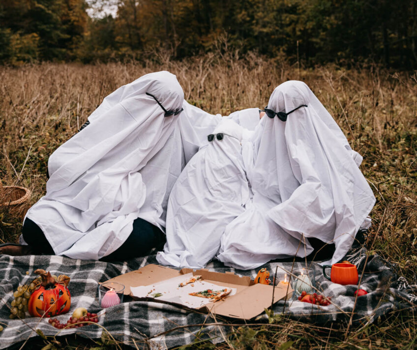 Friends dressed as ghosts having a Halloween picnic outdoors