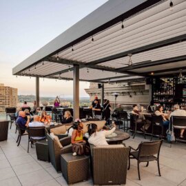 Guests with drinks on a busy rooftop at dusk in Cincinnati